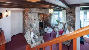 Un salon chaleureux avec des murs en pierre, une cheminée et des sièges confortables.