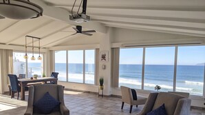 Ampla sala de estar com vista para o oceano, equipada com poltronas e mesa de centro.