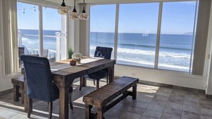 Uma zona de refeições com vista para o oceano, com uma mesa e bancos de madeira.
