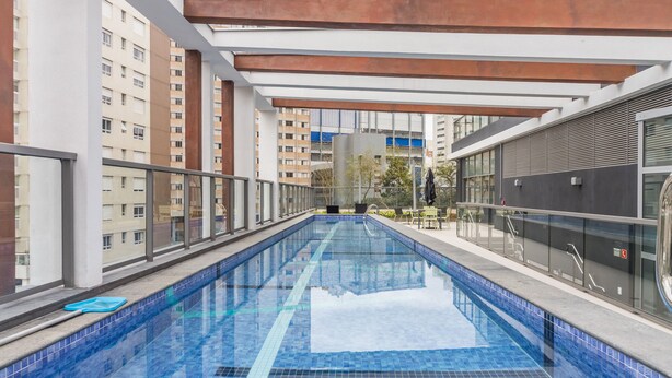 An indoor swimming pool with clear blue tiles, surrounded by glass railings and modern architecture. - Charlie Domy Paraíso (São Paulo)