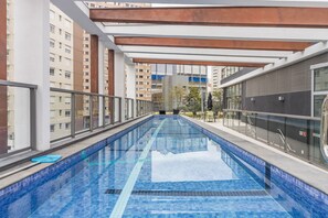 Une piscine intérieure aux carreaux bleu clair, entourée de rampes de verre et dotée d’une architecture moderne.