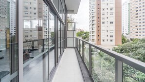A modern apartment building with a glass balcony, large windows, and a view of other high-rise buildings. - Charlie Domy Paraíso (São Paulo)