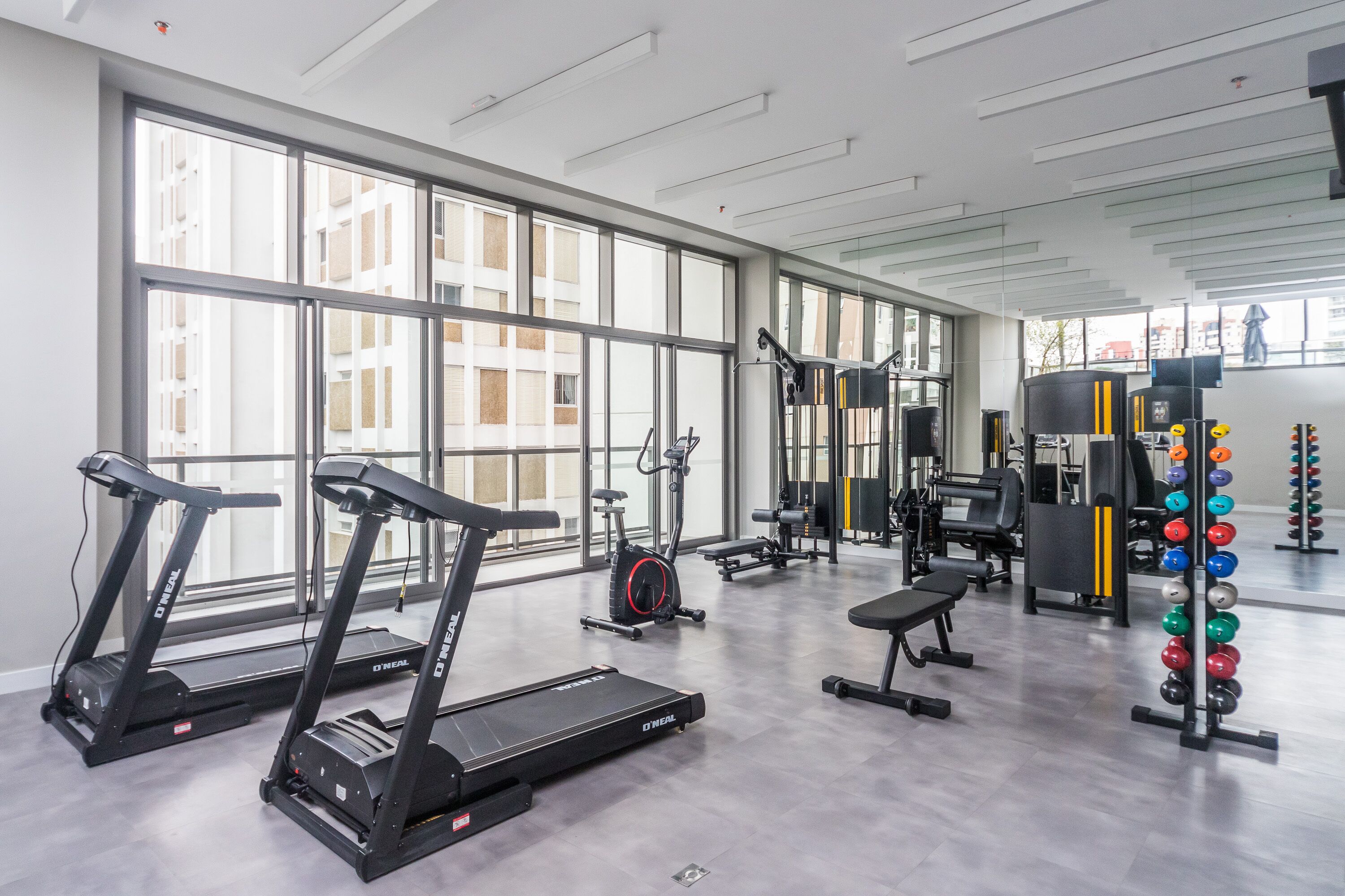 A modern gym with treadmills, weight machines, and a squat rack.