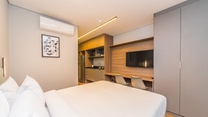 A modern hotel room with a large bed, a kitchenette, and a flat-screen TV. - Charlie Domy Paraíso (São Paulo)