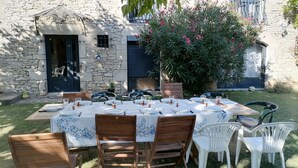 An outdoor dining area with a stone wall, a wooden table set for six, and chairs. - 3 Bedroom Private vacation home in PINSAC (PINSAC)