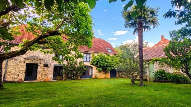 A stone building with a red-tiled roof, a well-maintained lawn, and a palm tree. - 3 Bedroom Private vacation home in PINSAC (PINSAC)