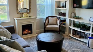 A cozy living room with a fireplace, comfortable seating, a television, and a bookshelf.