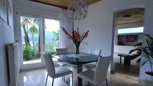 A modern dining area with a glass table, white chairs, and a decorative vase with flowers.
