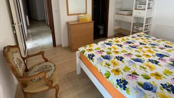 Un dormitorio con una cama, un aparador de madera, un espejo, un armario y una silla.