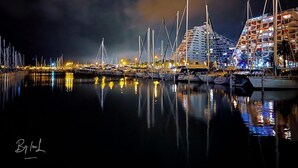 A marina at night with boats docked and buildings illuminated. - Renovated Boho Studio ☀ Pool | Beach | Queen-size bed (La Grande Motte)