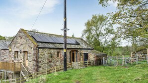 A stone farmhouse with a wooden door, a small porch, and a metal gate.