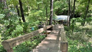A wooden bridge in a forested area with a covered structure in the background. - Family friendly lake front home with private dock in a cove (Winchester)