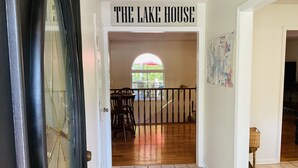 A hallway leading to a room labeled "THE LAKE HOUSE" with a view of a patio and a window overlooking greenery. - Family friendly lake front home with private dock in a cove (Winchester)