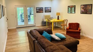 A living room with a brown leather sofa, a yellow dining table with chairs, a red armchair, and a sliding glass door leading to a deck. - Family friendly lake front home with private dock in a cove (Winchester)