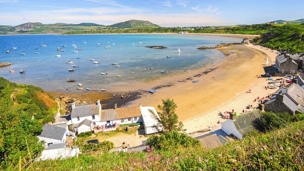 A coastal village with a sandy beach, boats in the water, and houses with sloped roofs. - An eco-friendly holiday bungalow near Abererch Beach on the Llyn Peninsula. (Pwllheli)