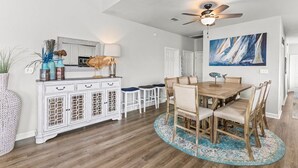 A dining area with a wooden table and chairs, a white cabinet with decorative items, and a ceiling fan. - Orange Beach, 4 Master Suites, short drive to Beach. Walk to Zekes and SweetCone (Orange Beach)
