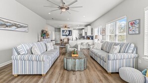 A spacious living room with striped sofas, a central coffee table, and a ceiling fan. - Orange Beach, 4 Master Suites, short drive to Beach. Walk to Zekes and SweetCone (Orange Beach)
