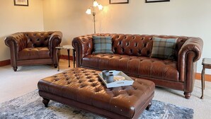 A living room with a brown leather sofa, a matching ottoman, and a small side table.