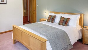 A bedroom with a wooden bed, a nightstand, a lamp, and a door with an archway.