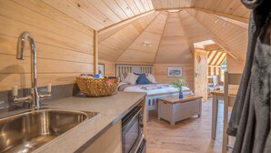 A cozy wooden cabin interior with a kitchen area, a dining space, and a bedroom. - Dol y Mynydd (The Mountain Meadow)-QU7521 (Abergele)