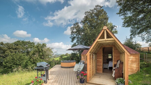 A wooden cabin with a hot tub, a barbecue grill, and a bed with a view of the surrounding landscape. - Dol y Mynydd (The Mountain Meadow)-QU7521 (Abergele)