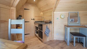 A compact kitchen with wooden walls, a sink, a microwave, and a small dining area with a bench. - Dol y Mynydd (The Mountain Meadow)-QU7521 (Abergele)