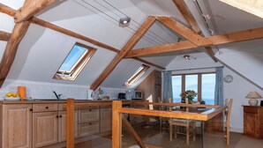 Une cuisine spacieuse avec des poutres en bois, un coin repas offrant une vue agréable et une grande fenêtre.
