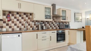 Una cocina moderna con armarios color beige, lavavajillas, horno y microondas.