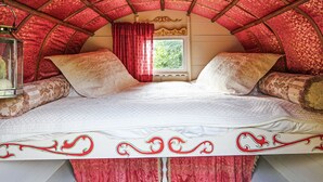 A cozy, arched room with a bed, red curtains, and a window. - 1 bedroom accommodation in Malpas (Malpas)