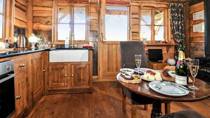 A rustic wooden cabin interior with a kitchen, dining area, and a fireplace. - 1 bedroom accommodation in Malpas (Malpas)