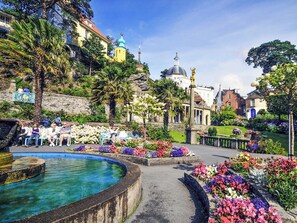 Un giardino con una fontana, panchine e una varietà di fiori.