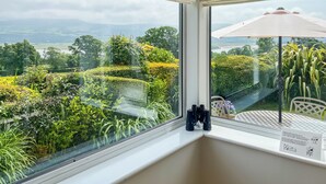 A room with a large window overlooking a landscaped garden and distant hills. - 2 bedroom accommodation in Portmeirion (Portmeirion)