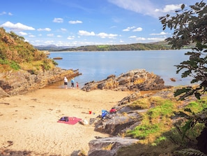 Une plage avec un terrain rocheux, une zone sablonneuse et une étendue d’eau calme.