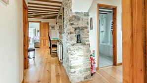 A hallway with wooden floors, a stone wall, a wooden door, and a bathroom visible in the background. - 3 bedroom accommodation in Cerbid (Cerbid)