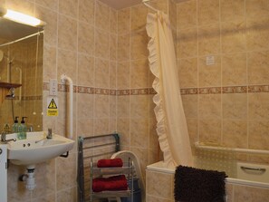 A bathroom with a sink, mirror, shower curtain, and a towel rack with towels. - 3 bedroom accommodation in Llanfair Caereinion, near Welshpool (Llanfair Caereinion, near Welshpool)