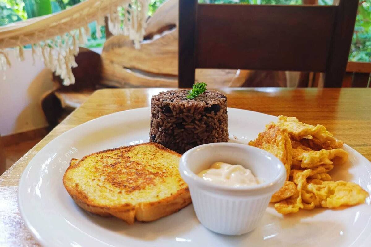 A plate with toast, a rice cake, scrambled eggs, and a small bowl of butter.