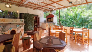 An indoor dining area with wooden furniture and a view of lush greenery outside. - Hotel Boutique D Angelo (Manzanillo)