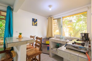 A compact kitchen with a refrigerator, a stove, and a window with curtains. - Hotel Boutique D Angelo (Manzanillo)