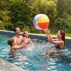 A family playing with a beach ball in a swimming pool surrounded by greenery. - Hotel Boutique D Angelo (Manzanillo)