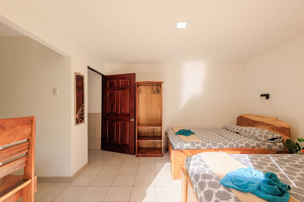 A bedroom with two beds, a wooden wardrobe, and a bench.