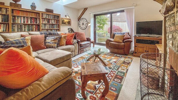 Una sala de estar acogedora con chimenea, estantería, ventana grande y televisor.