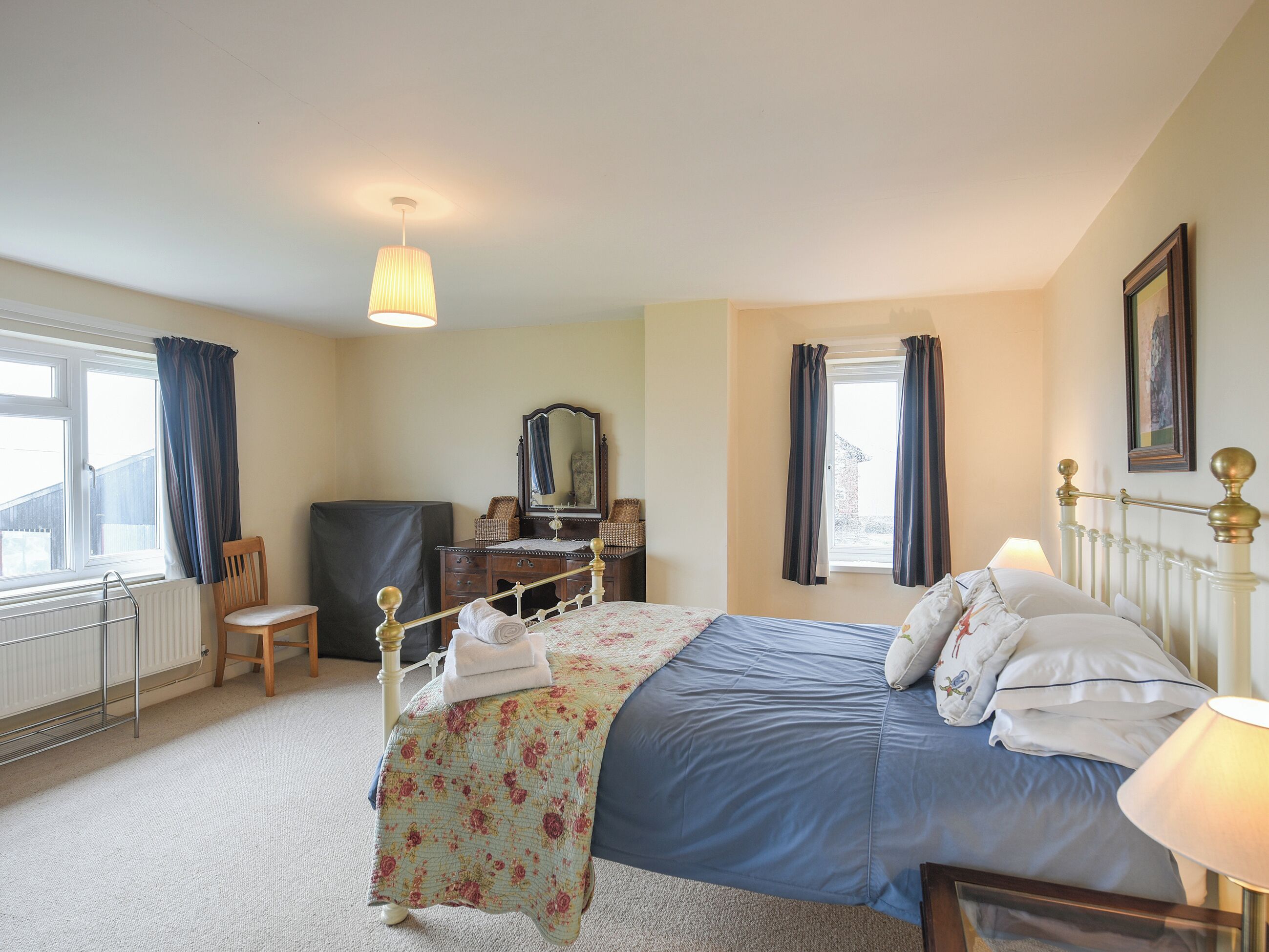 Une chambre à coucher avec un lit, une commode, une chaise, un bureau et une fenêtre.