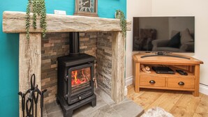 Une pièce avec une cheminée en pierre, un téléviseur et un meuble TV en bois.