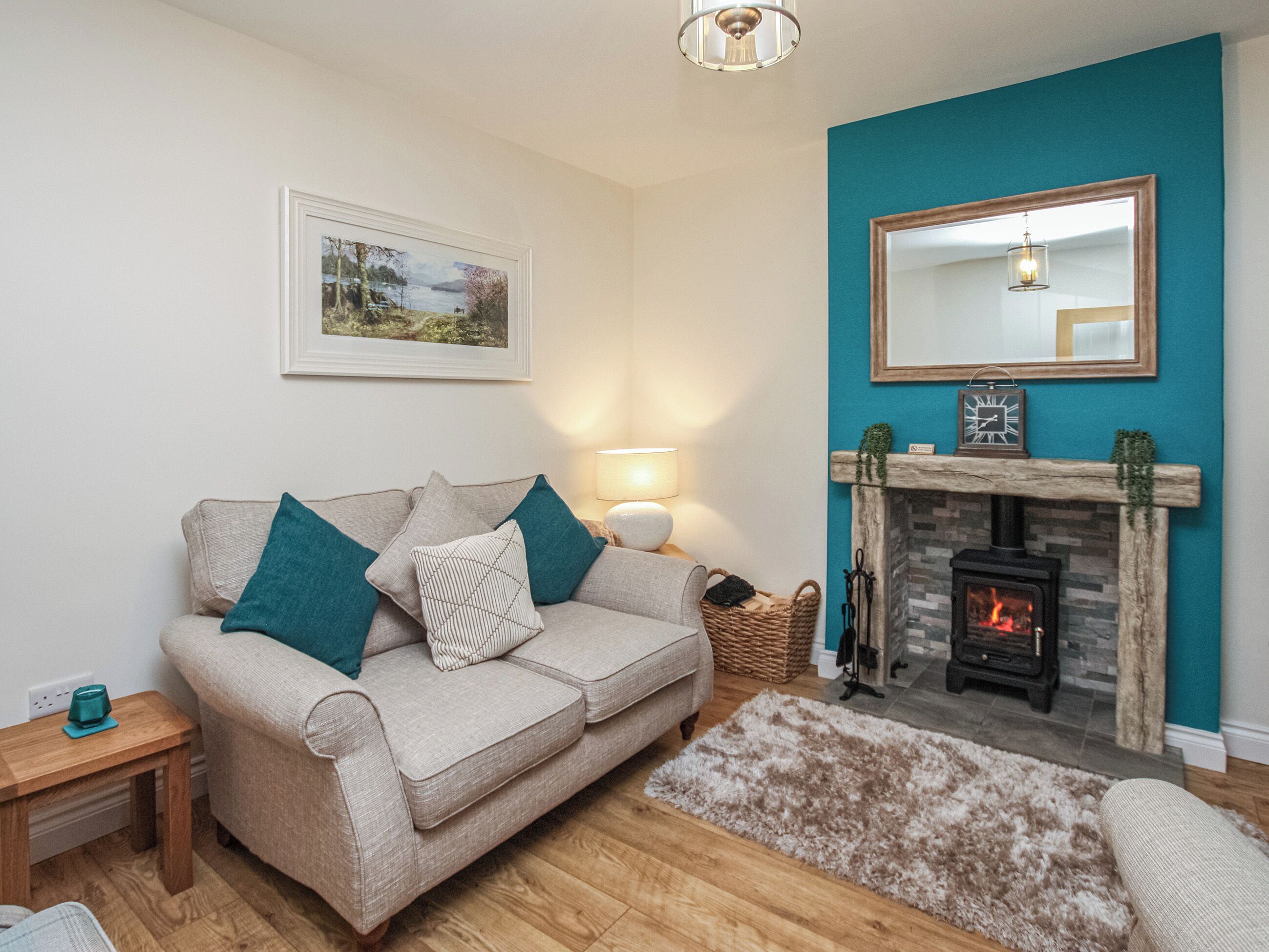 A living room with a sofa, a fireplace, and a wall-mounted mirror.