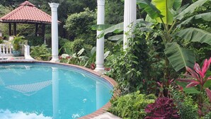 A pool surrounded by lush greenery, white columns, and a gazebo. - Your Private Slice of Paradise! (Luquillo)