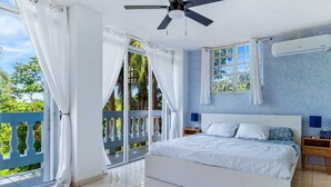 A bedroom with a bed, a ceiling fan, an air conditioning unit, a nightstand, and a view of the outdoors. - Your Private Slice of Paradise! (Luquillo)
