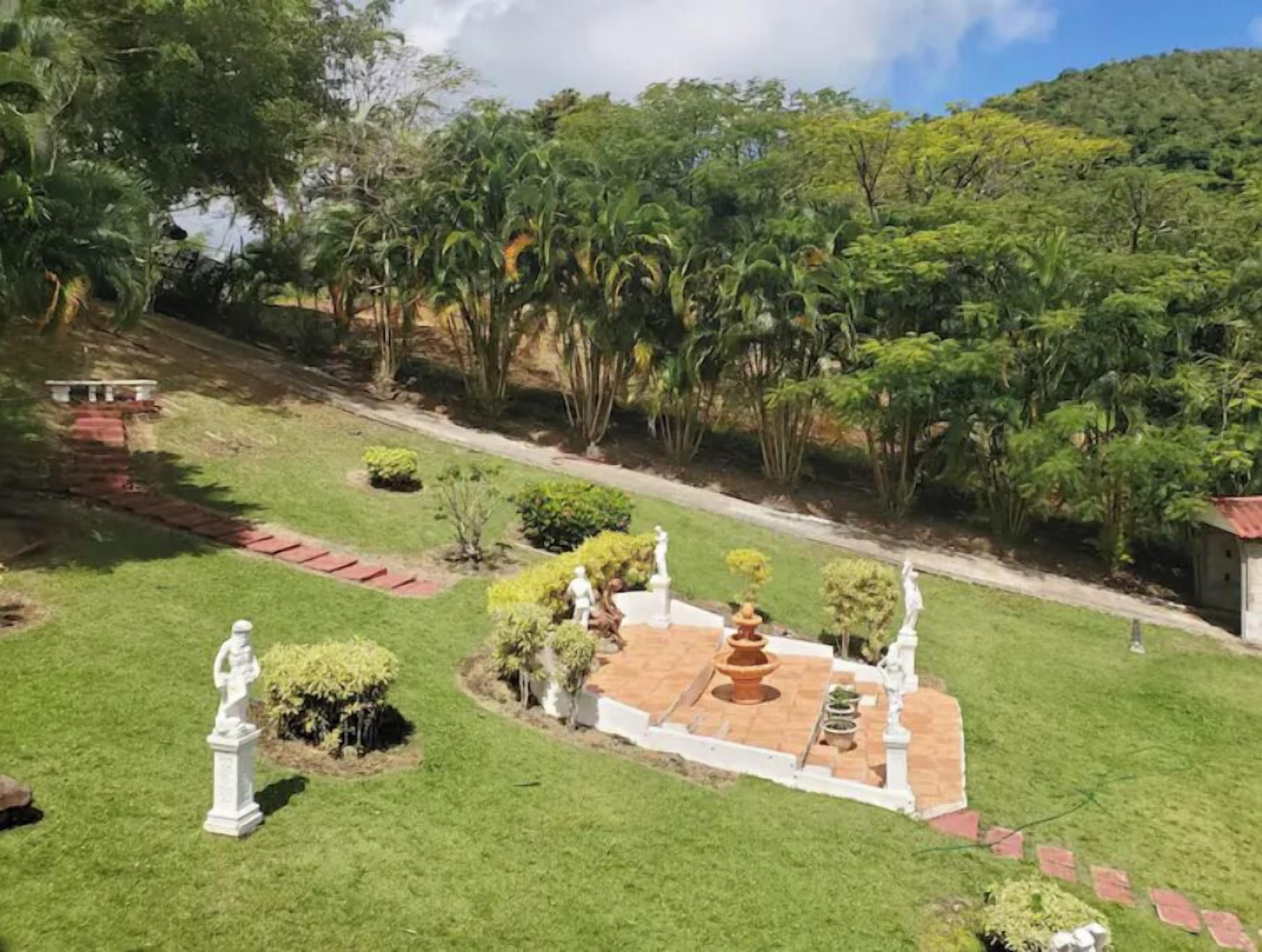 A well-maintained garden with statues, a fountain, and a pathway.