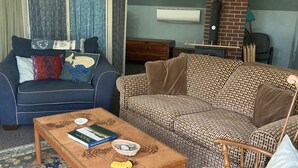 A cozy living room with a blue sofa, a patterned sofa, a wooden coffee table, and a rocking chair. - Studio Apartment on lake near Camden, Maine. (Lincolnville)