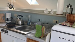 A compact kitchen with a sink, a kettle, a coffee maker, and a refrigerator. - Studio Apartment on lake near Camden, Maine. (Lincolnville)