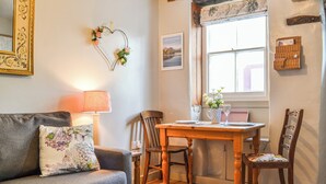 A cozy living room with a sofa, a wooden dining table, and two chairs. - 1 bedroom accommodation in Keswick (Keswick)
